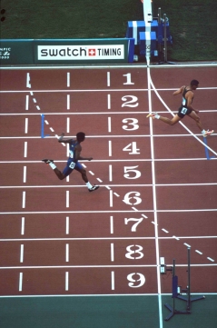 Sprinters as they cross the finish line during a race at the 2000 Sydney Paralympic Games von Australian Paralympic Committee via Wikimedia Commons (https://commons.wikimedia.org/wiki/File:141100_-_Athletics_track_finish_line_from_above_-_3b_-_2000_Sydney_race_photo.jpg), cc (https://creativecommons.org/licenses/by-sa/3.0/deed.en)